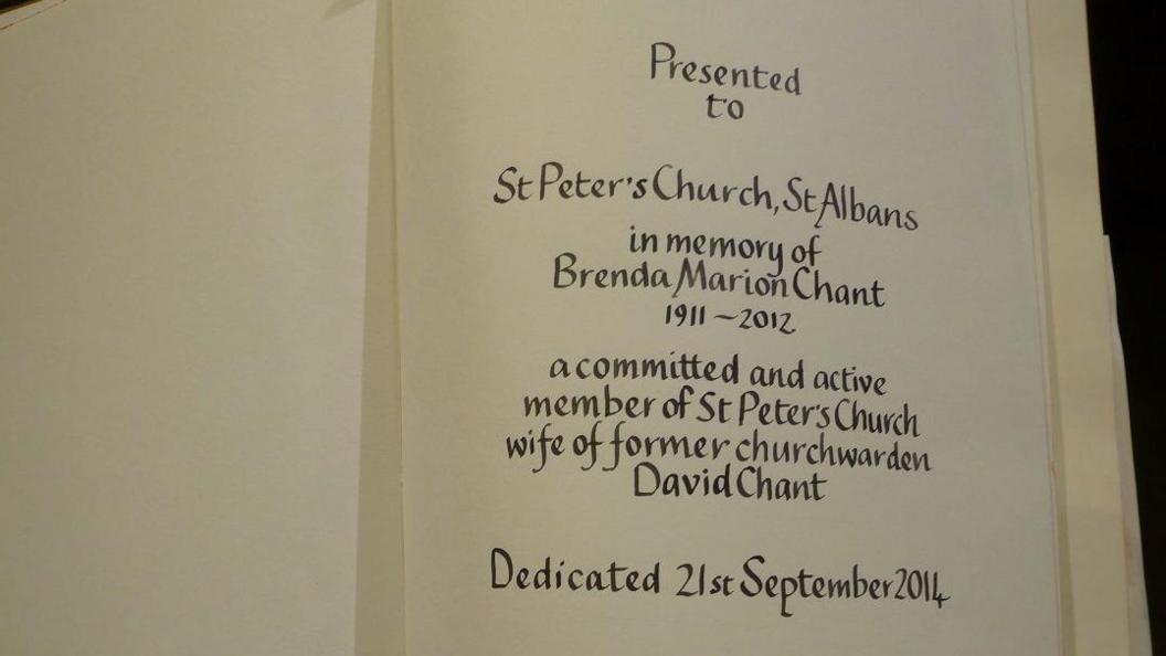 A bible opened at the first page, revealing the inscription "Presented to St Peter's Church, St Albans, in memory of Brenda Marion Chant, 1911-2012, a committed and active member of St Peter's Church, wife of former churchwarden David Chant. Dedicated 21st September 2014."