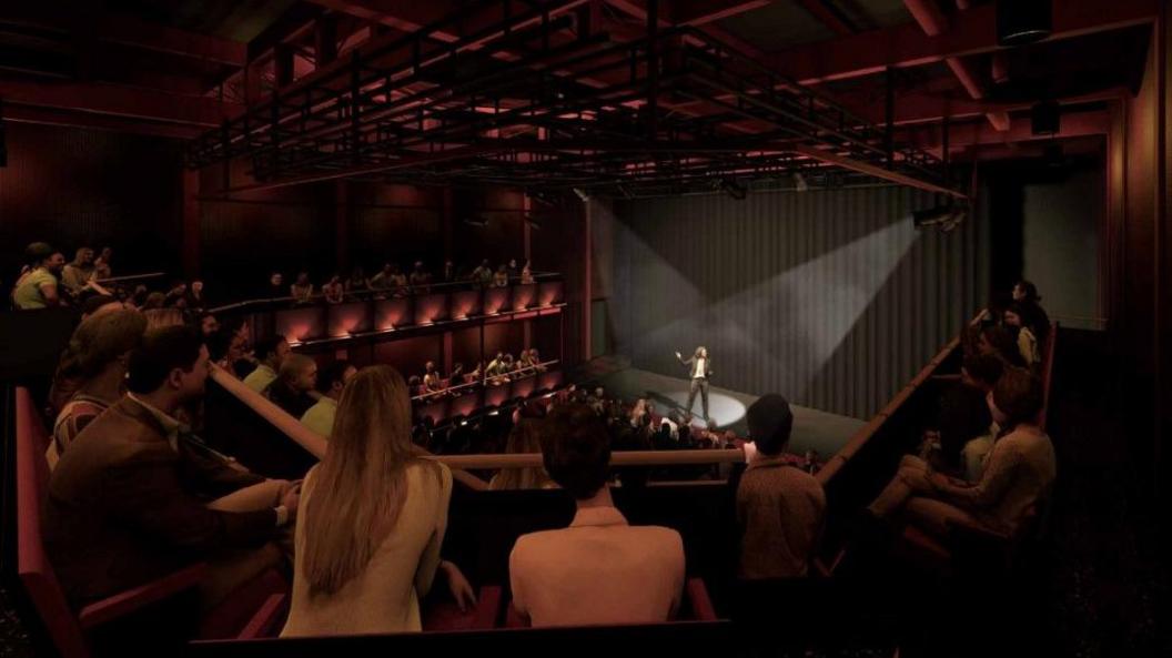 A computer generated image of what the inside of the theatre might look like. A man stands under a spotlight on a stage. The auditorium is quite small, with red seats on several levels.