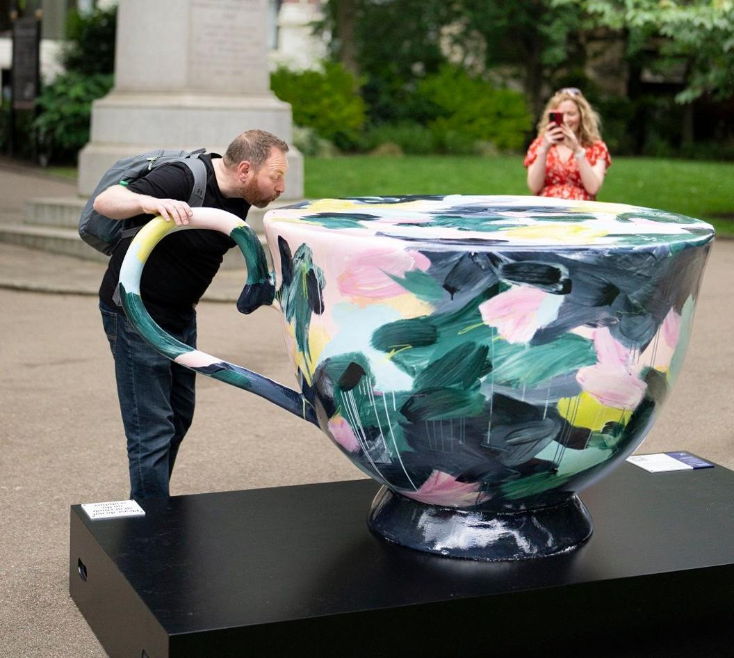 A man drinks from a large sculpture of a cup of tea 