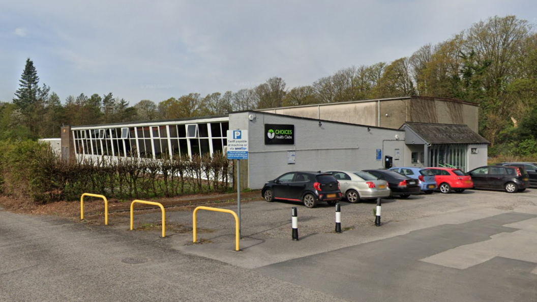 Choices Health Club from a side on view. The building design is single-storey concrete with panelled windows on the front face. There are a number of cars parked outside. 