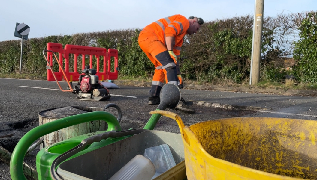 A worker fixing a pothole