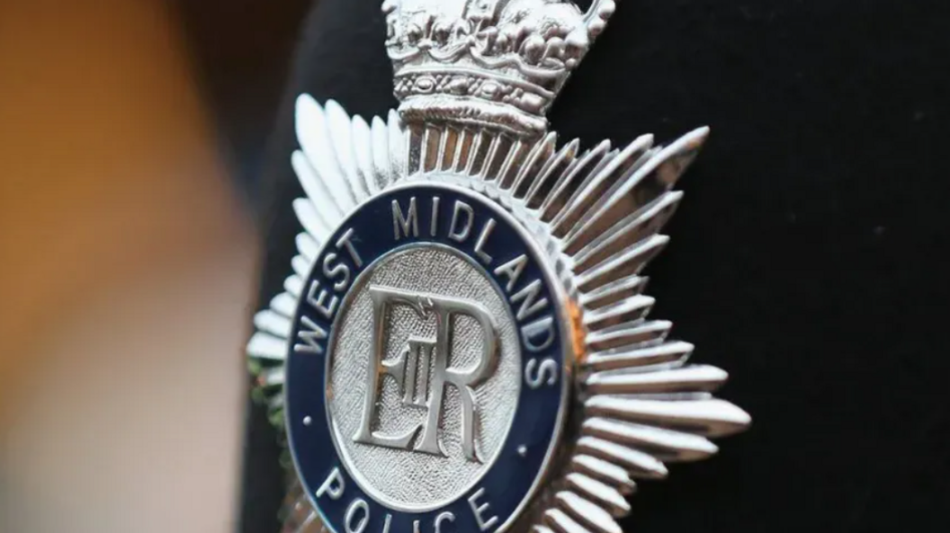 A close-up of a silver police badge, with the words West Midlands Police around the edge