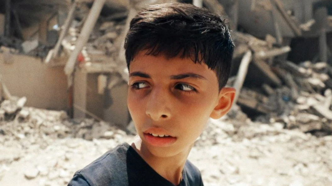 Abdullah Al-Yazouri walking in front of a demolished building