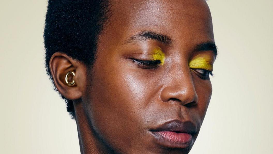 A close-up of idiosyncratic    wearing yellowish  oculus  shadow. In their receptor  is simply a golden  loop-style ear-plug.
