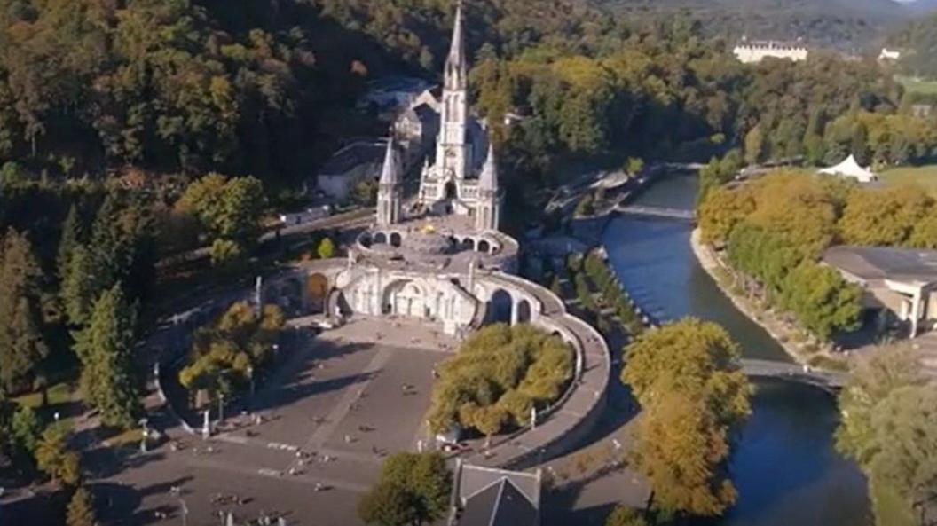 Drone shot of Lourdes surrounded by woodland and a river