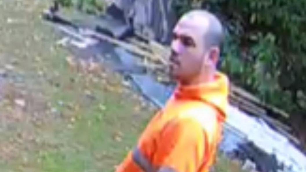 Scammer William Smith caught on one of his victim's CCTV. He has a shaved head, stubble and is wearing a high visibility jacket.
