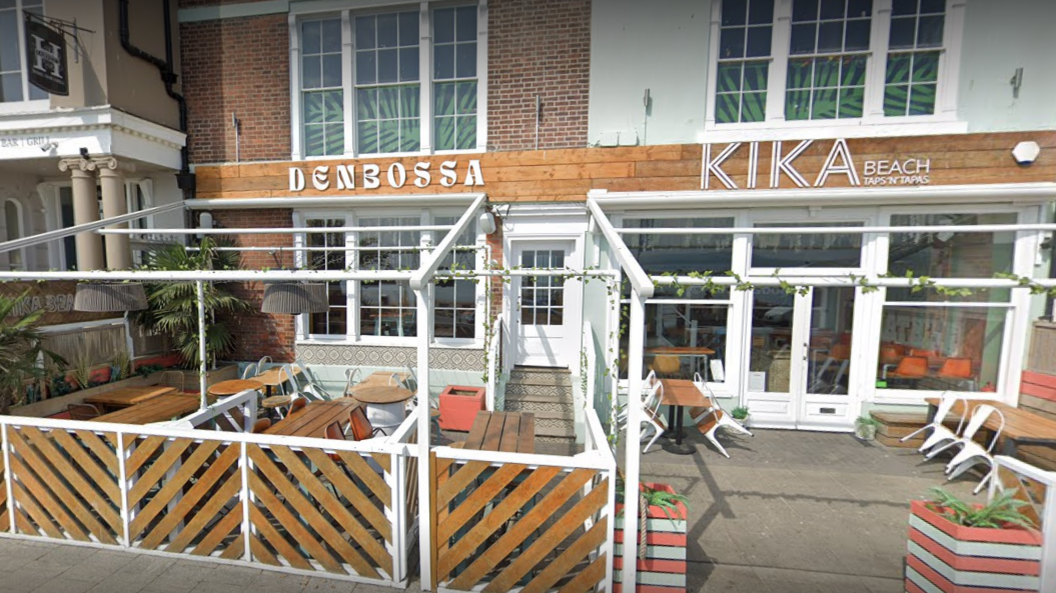 An exterior scene of the deserted Kika Beach bar with wooden outside seating.