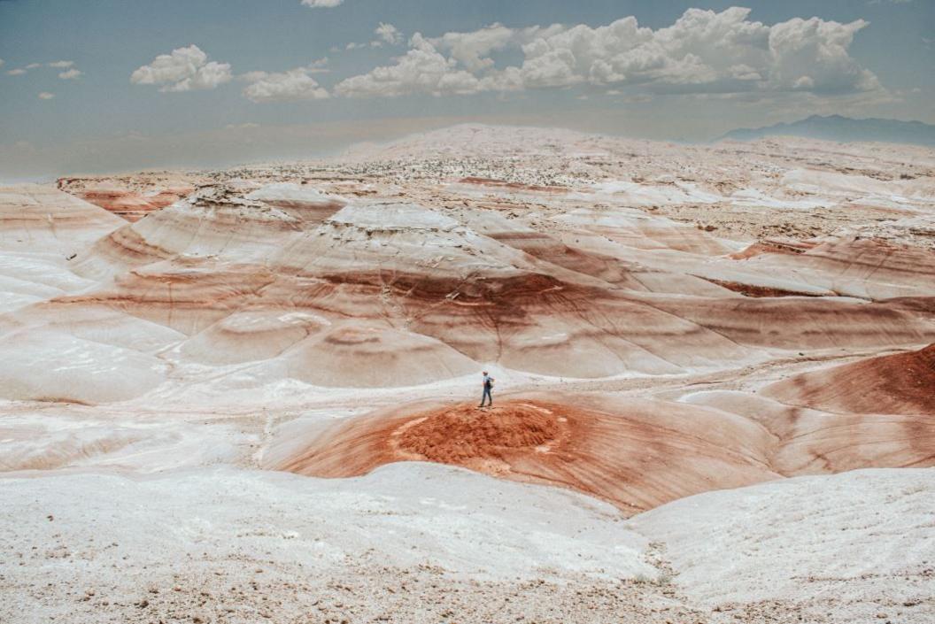 walker in the red streaked Bentonite Hills, a remote hiking area in Utah, USA.