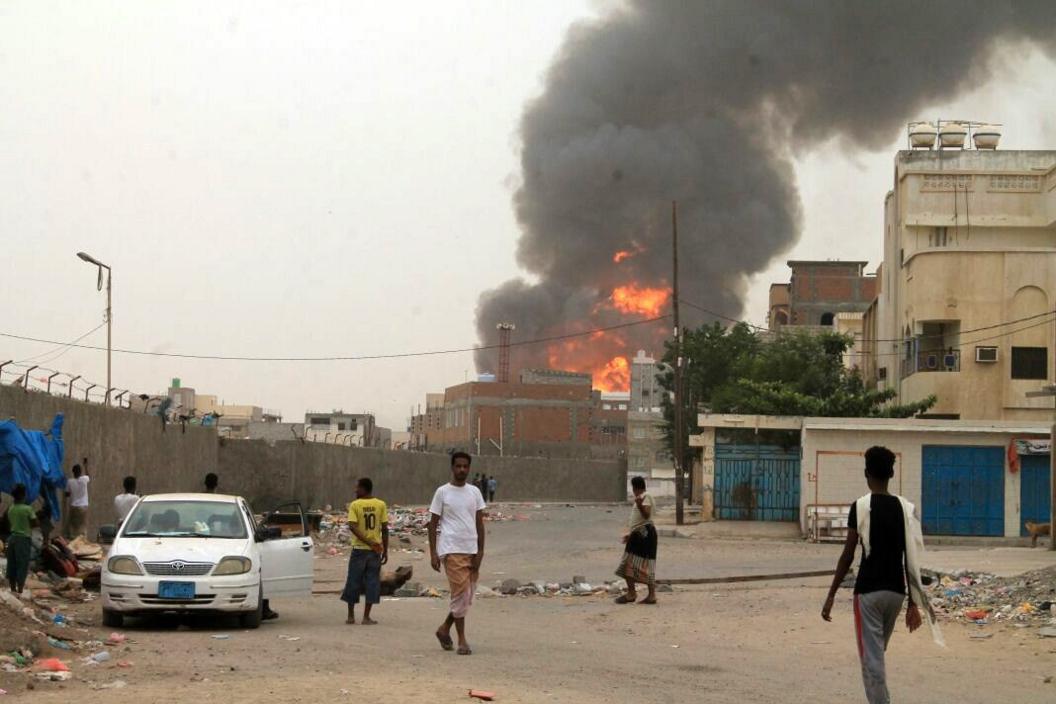 Yemenis watch as smoke billows following clashes between fighters loyal to exiled President Abdrabbuh Mansour Hadi and Houthi rebels in Aden