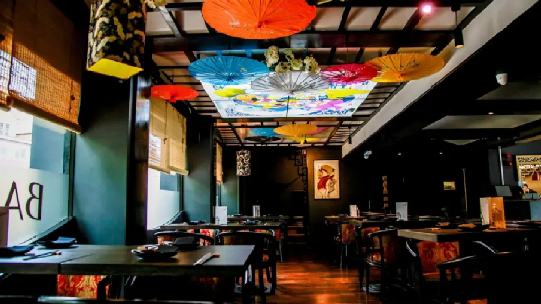 Inside of Bambudda restaurant in Darlington. It is an Asian restaurant and is decorated with black tables and chairs and has umbrellas hanging from the ceiling.