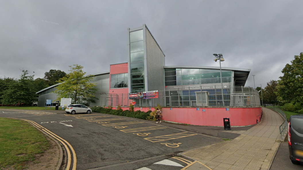 Pingles Leisure Centre, a glass-fronted building with pink painted walls and a metallic flank