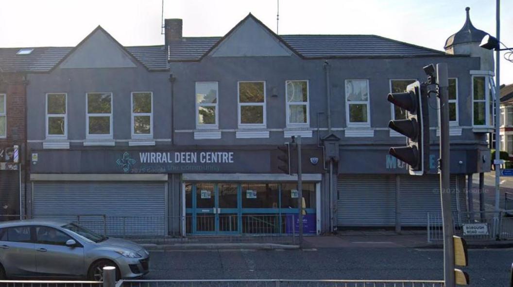 A grey terraced building with a sign which says Wirral Deen Centre in white writing