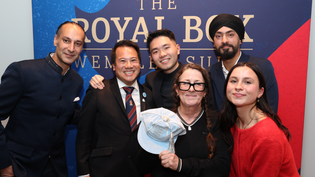 Three men stood behind two women. One of the women is holding a blue honorary England cap