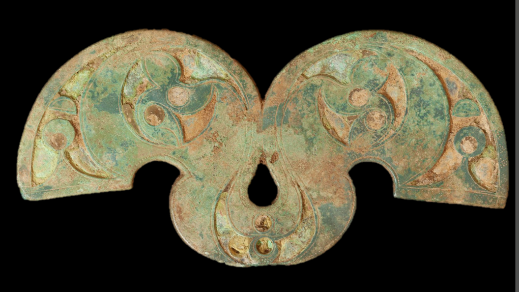 A turquoise- and copper-coloured brooch with some ornamentation.