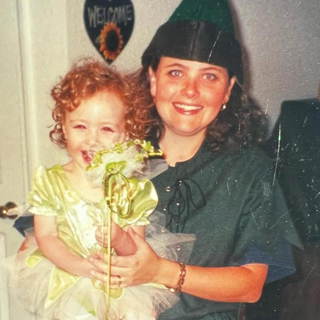 A childhood photo of Chappell Roan, in which she sits on her mother's knee in a frilly yellow-green dress.