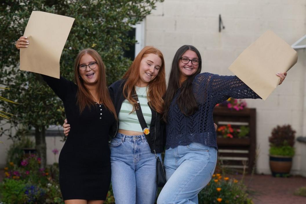 Three women holding certificates and looking happy