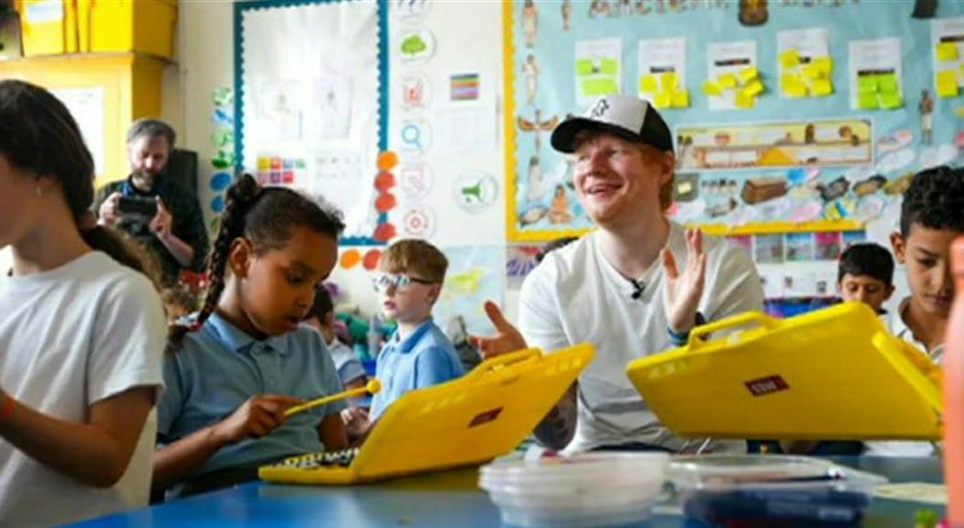 Ed Sheeran sitting with children at primary school 