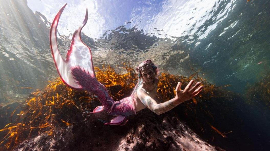 Lukas Stevenson under water wearing a mermaid tail