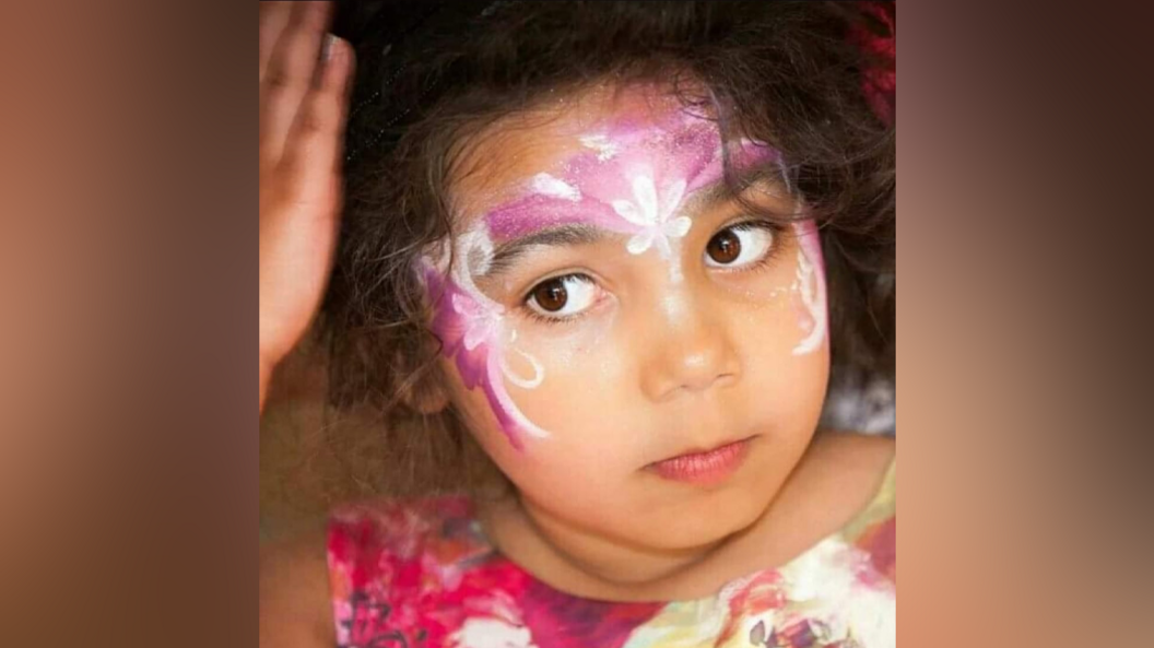 Amira when she was younger in pink face paint and a pink top.