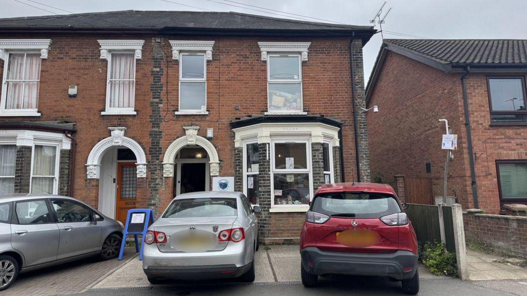 A view of the animal centre from the road. It looks like a terraced house and two cars are parked on its driveway.