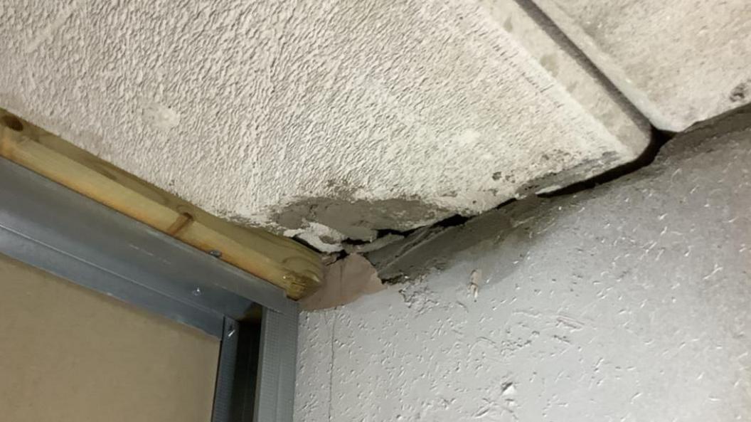 Concrete ceiling panel with damage in a corner. Cement appears to have been used to patch it.