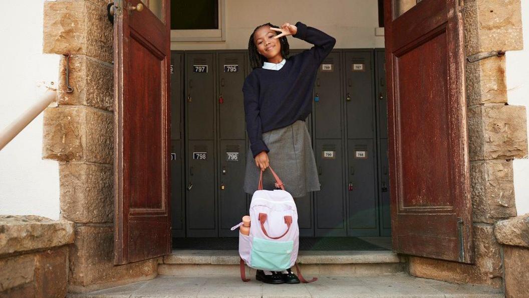 Girl holding bag and posing with a peace sign.