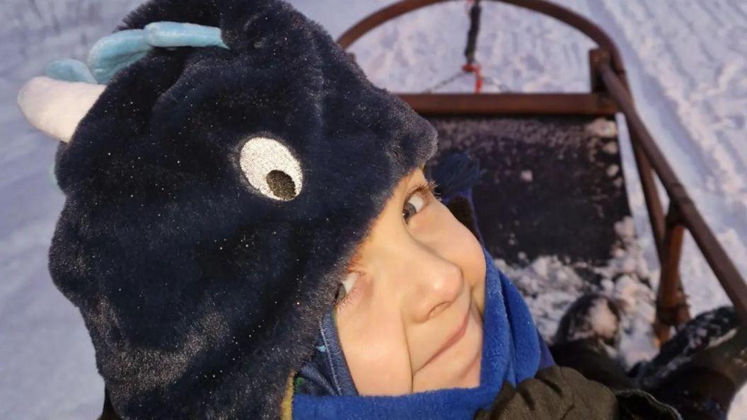 Henry smiling on a husky sledge ride in the snow 