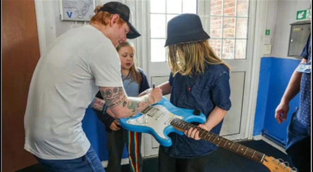 Ed Sheeran signing guitars with children at primary school 