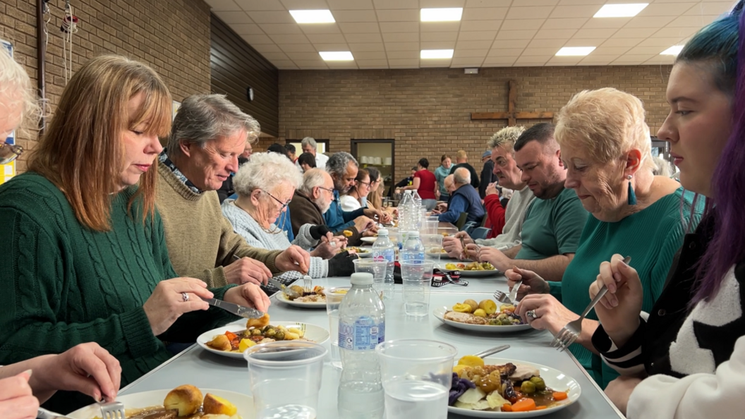 Diners eat a Sunday lunch in a church hall