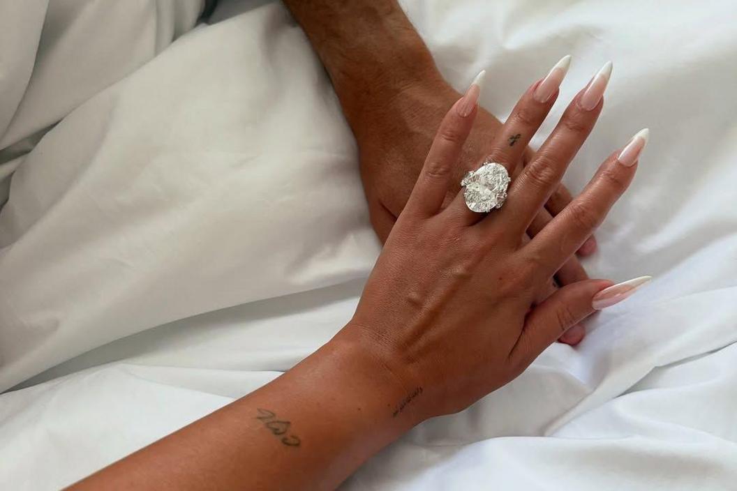 A picture showing two people's arms on a bed, with Gio's huge engagement ring visible on her finger.