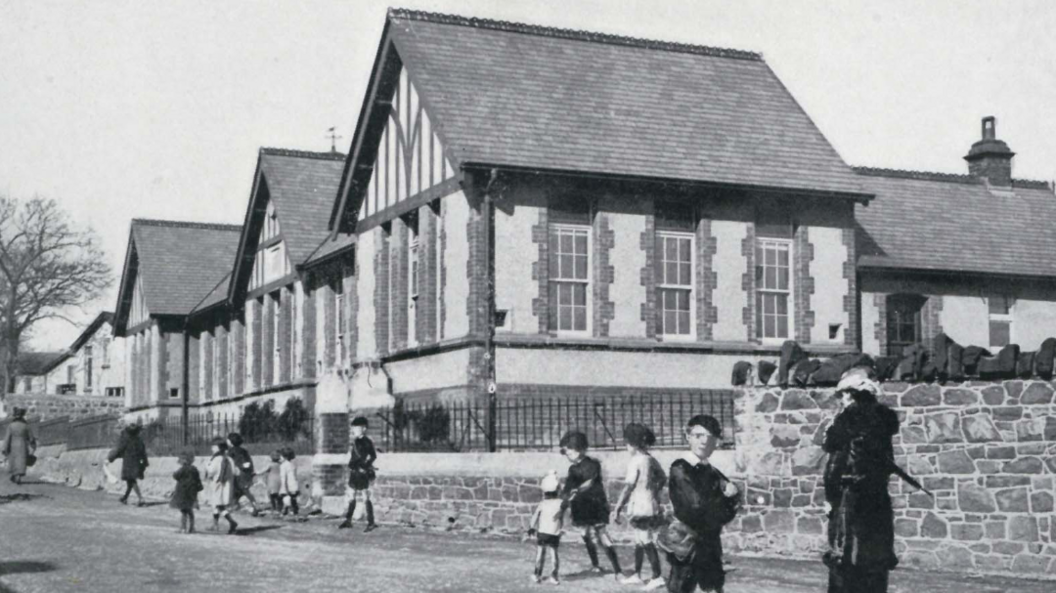Black and white photo of children playing outside a school.