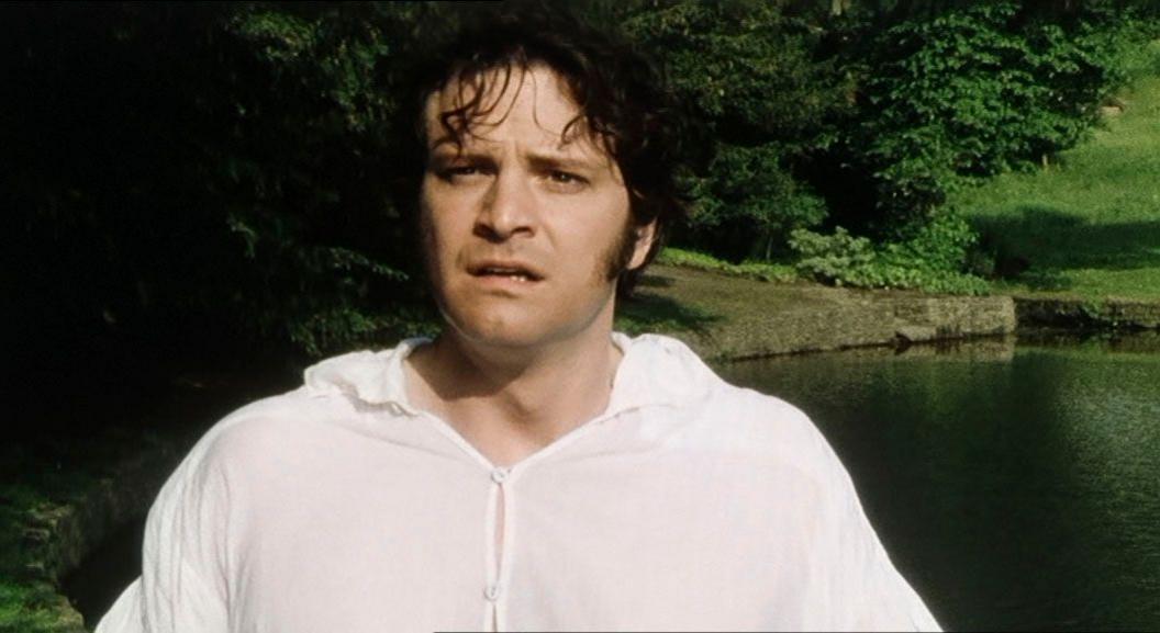 a still from 1995's pride and prejudice featuring colin firth standing in front of a lake in a wet white shirt