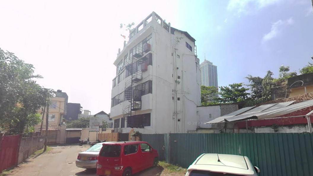 A view of a four storey white building off an alleyway in Sri Lanka