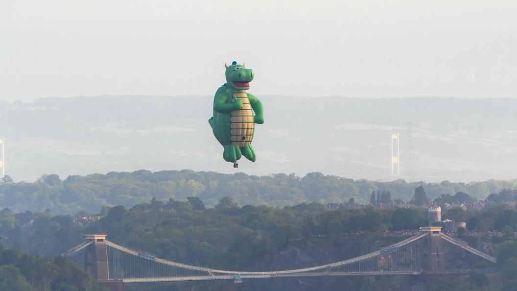 A giant green dragon flying above the Clifton Suspension Bridge in Bristol.