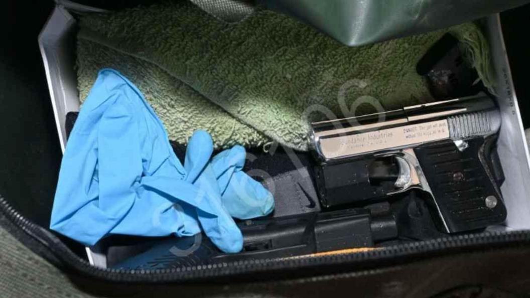 A picture showing a silver handgun with a black handle, as well as blue rubber gloves and other black equipment.