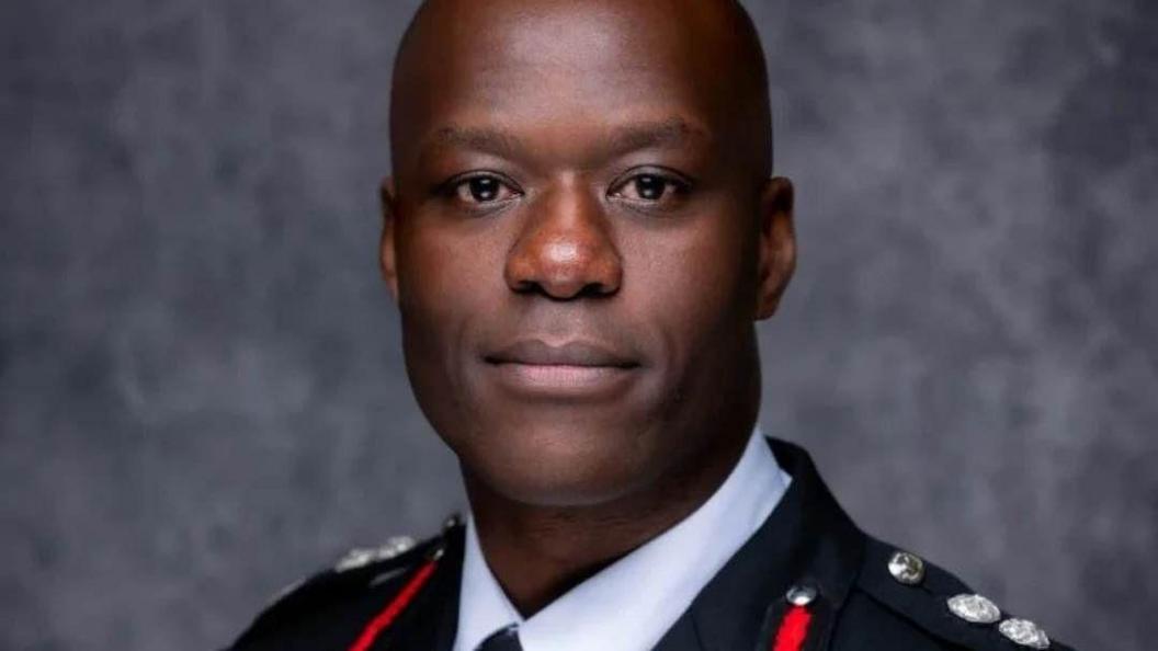 Wayne Brown in his fire officer uniform in front of a grey wall