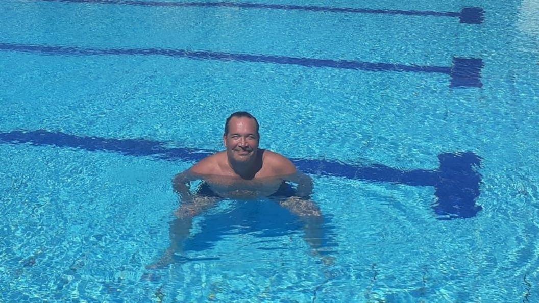 Mark O'Brien standing in a swimming pool, smiling