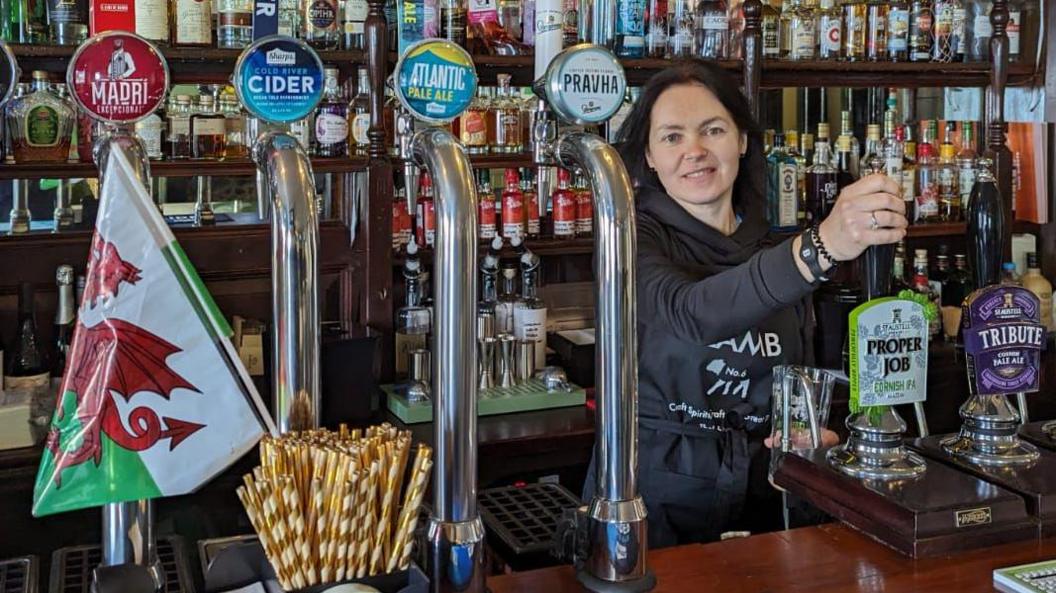 Vladyslava Krapyvka behind the bar of The Lamb pub 