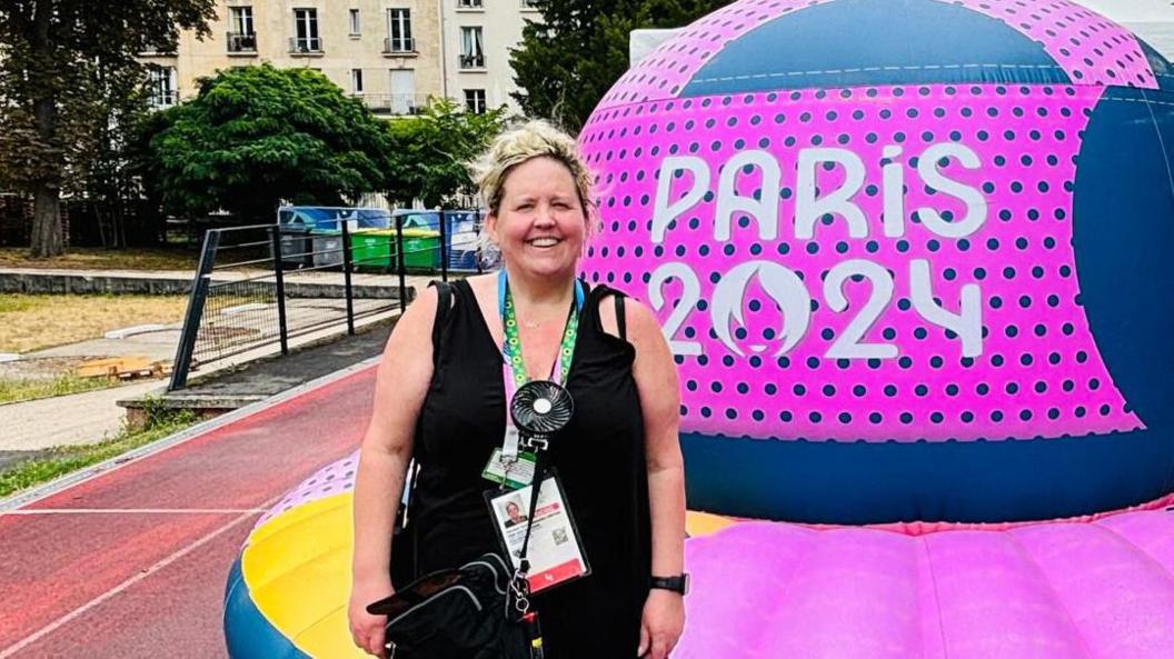 Olympic volunteer Karolyn Gaston standing beside a Paris 2024 branded dome