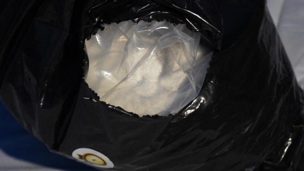 A sack is open at the top and white powder can be seen.