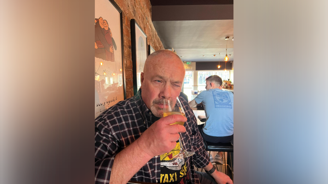 A man sniffs a wine glass in a pub