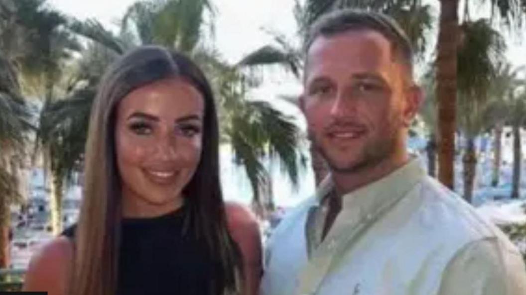 David Richards in a white shirt pictured with a woman and palm trees in the background