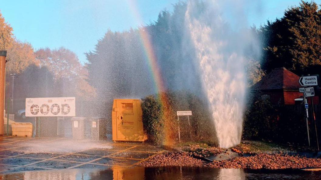 A burst water pipe with water shooting out from the ground outside a small fire station in East Leake in Nottinghamshire.
