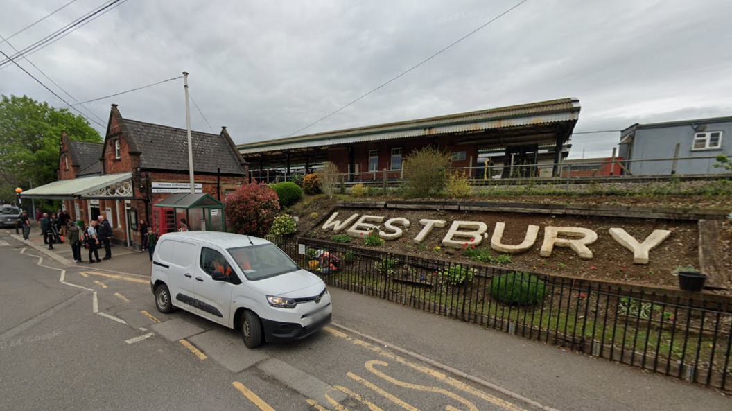 Westbury train station, with the word Westbury in large white letters on a hill in front of the platforms