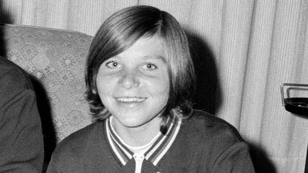 A 14-year-old smiling Gill Sayell with short hair wearing a football kit