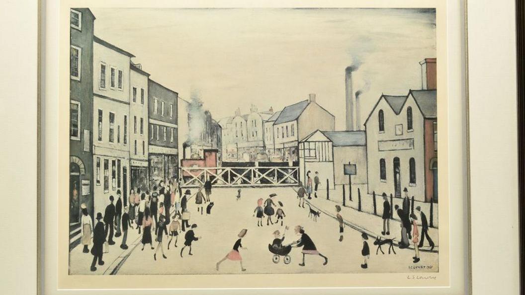 A print showing figures in a street with a level crossing in the background in between buildings.
