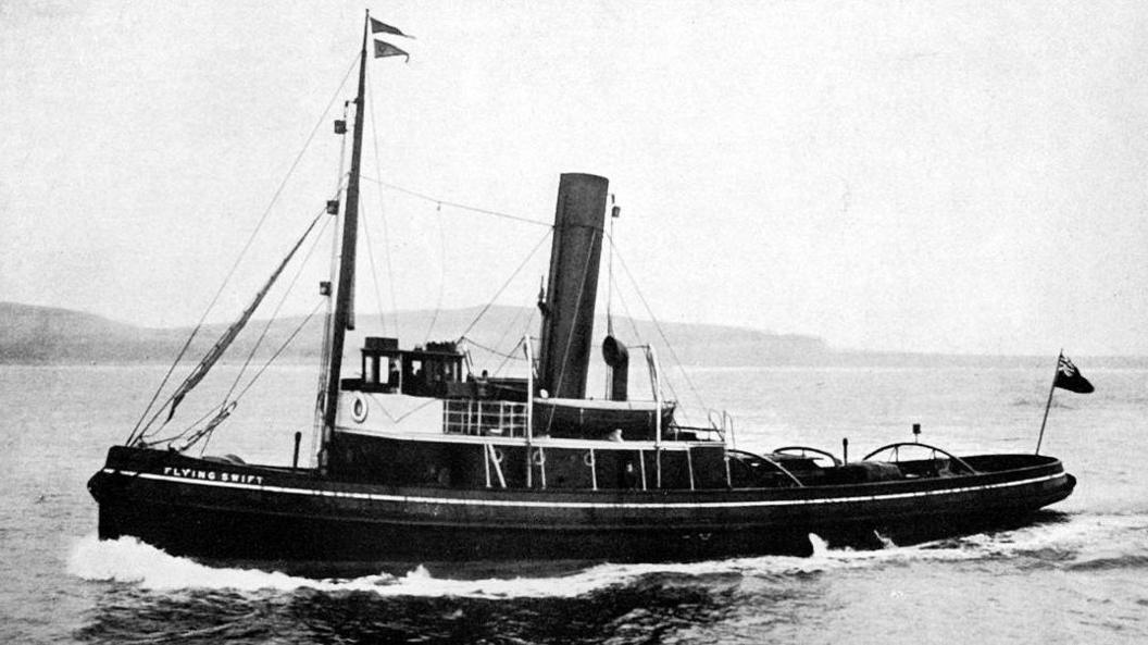 A black and white image of a tug, Flying Swift, out on the water with hills in the background