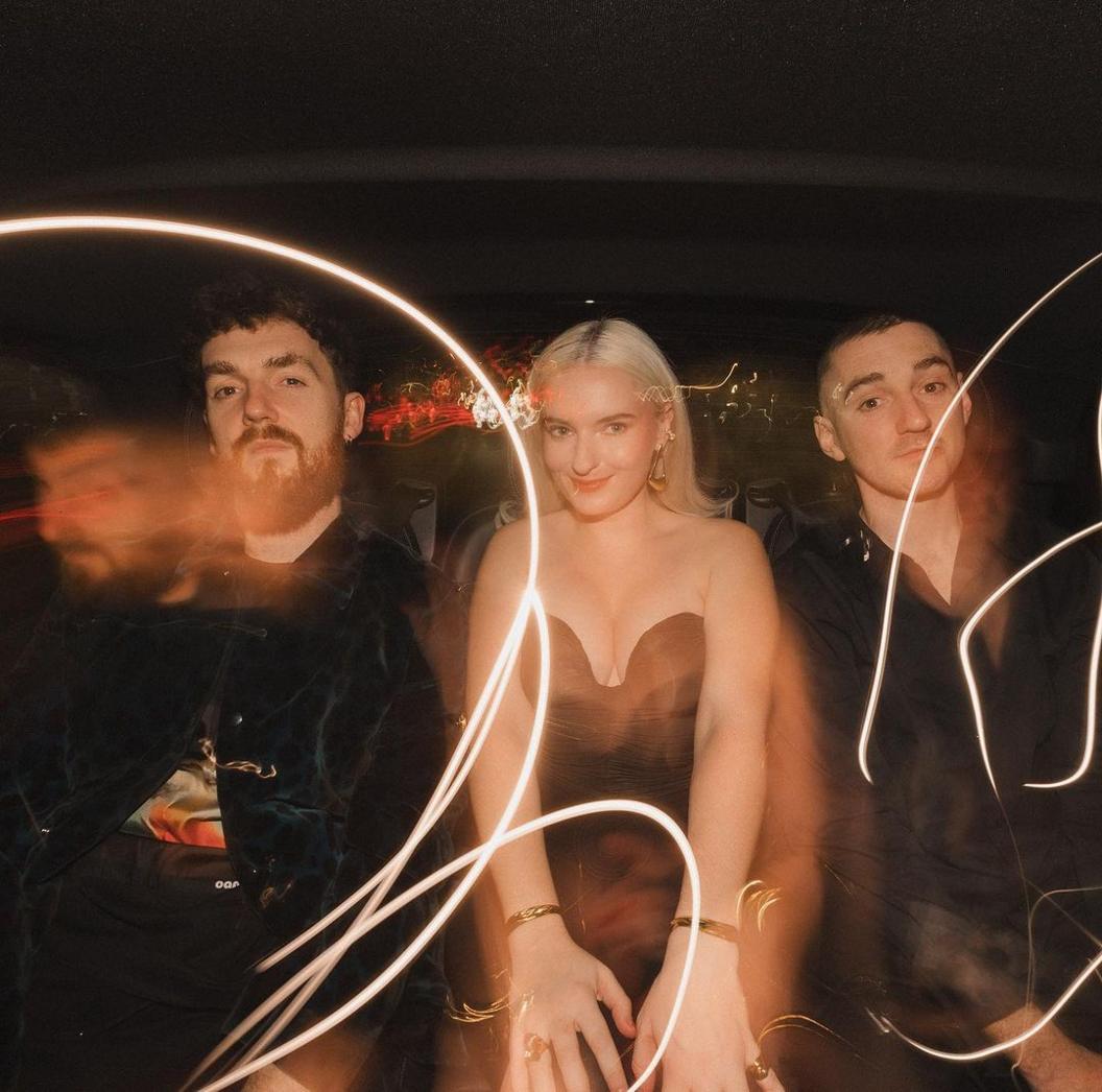 Shot of Clean Bandit in the back of a car, illuminated by flashes of light