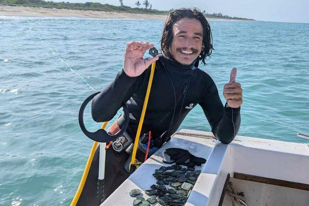 Diver holding one of the coins from the treasure. 