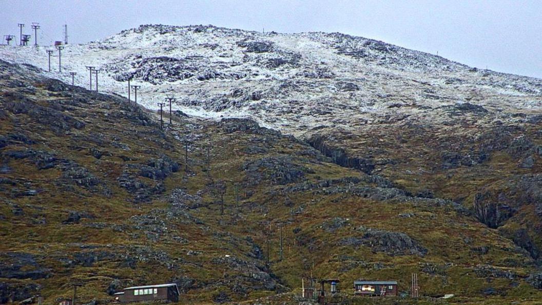 A dusting of snow on higher slopes with Glencoe Mountain ski centre's tows and buildings